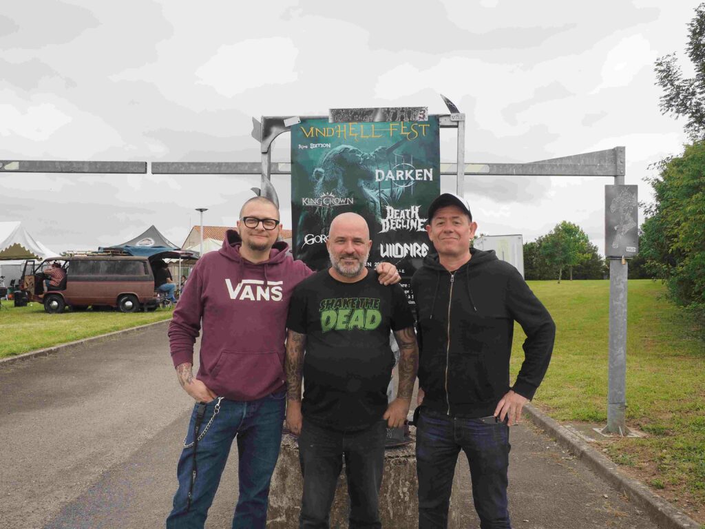 Le groupe de métal Shake the Dead devant l'affiche du Vind'Hell Fest III.